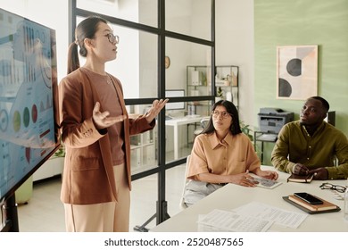 Multiracial team analyzing business data with professional presenting information in modern office conference room using technology and visual aids during daytime meeting - Powered by Shutterstock