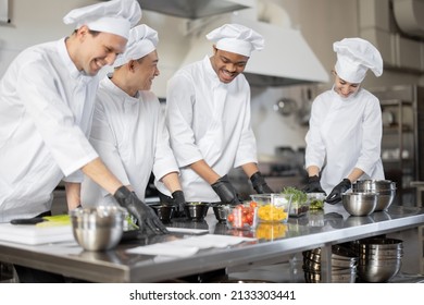 Multiracial team of cooks mixing ingredients for take away food in professional kitchen. Concept of dark kitchen for cooking for delivery. Idea of teamwork in a restaurant. Diverse people at job - Powered by Shutterstock