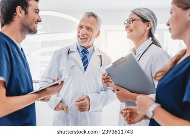 Multiracial team of doctors discussing patient standing in clinic foyer, learning new about illnesses, medical cases, diseases. Treatment and recuperation. Healthcare - Powered by Shutterstock