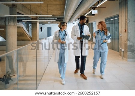 Multiracial team of doctors talking while walking in hallway of medical clinic.