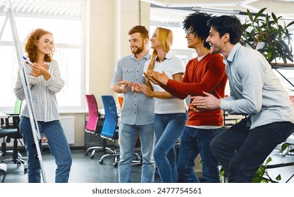 A multiracial team engages in a collaborative exercise, fostering teamwork and camaraderie. They appear to be enjoying a playful moment, clapping and smiling, possibly celebrating a milestone