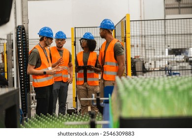 Multiracial team of engineers wearing safety vests and helmets discussing production process while standing next to a conveyor belt with glass bottles in a bottling factory - Powered by Shutterstock