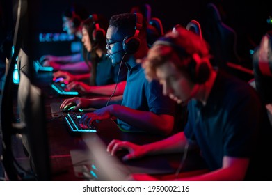 A Multi-racial Team Of Esports Athletes Conducts A Training Session Before An Online Shooter Tournament. Neon Light.