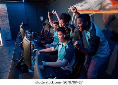 Multiracial Team Of Happy Professional Cyber Sports Gamers Celebrating Success Wile Raising Hands Up During Esports Tournament In Gaming Club
