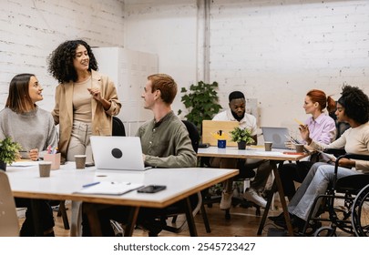 Multiracial team members are working together in a bright open plan office, demonstrating collaboration, diversity, and social inclusion in a professional environment