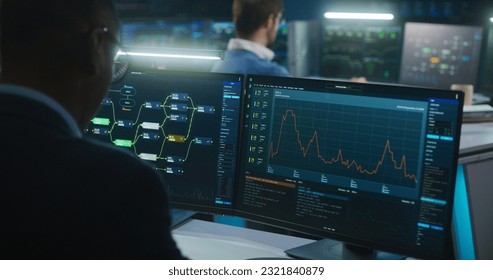 Multiracial team of IT software engineers work in monitoring office. Data server, blockchain network and live analysis charts displayed on computers and big digital screens. Concept of cyber security.