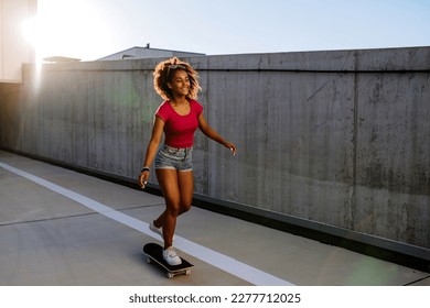 Multiracial teenage girl riding a skateboard in front of concrete wall, balancing. Side view. - Powered by Shutterstock