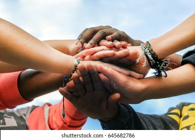 Multiracial teenagers joining hands together in cooperation