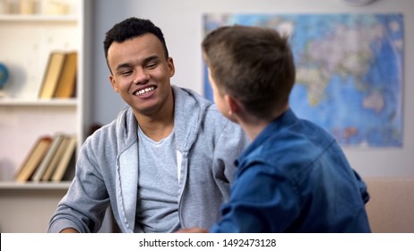 Multiracial Teenagers Making Up After Quarrel, Smiling Friends Sitting On Sofa