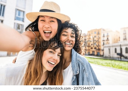 Multiracial three young women taking selfie portrait on city street - Happy female friends having fun together hanging outside - Life style concept with beautiful girls enjoying summer holidays 