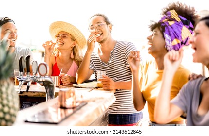 Multiracial trendy friends having fun drinking bear at sunset beach party - Summer joy and life style concept with young people at chiringuito happy hour - Warm bright filter with focus on mid guy - Shutterstock ID 2143612845