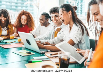 Multiracial university students sitting together at table with books and laptop - Happy young people doing group study in high school library - Life style concept with guys and girls in college campus