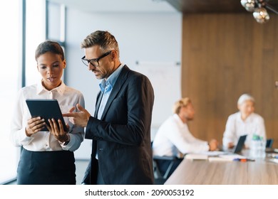 Multiracial woman and man using tablet computer during meeting in office - Powered by Shutterstock