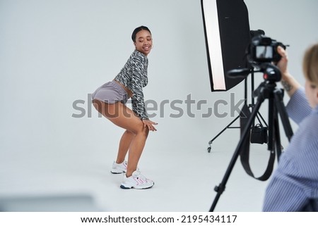 Multiracial woman twerking while photographer shooting her dance at the studio