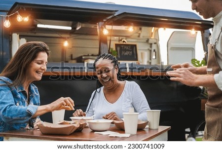 Adult women taking selfie at table near food truck