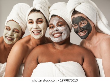 Multiracial Women Enjoy Spa Day Together With Beauty Face Mask While Wearing Towels - Multi Generational Friends With Different Skin Color And Bodys