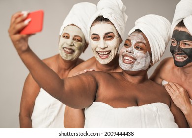 Multiracial women taking a selfie with smartphone - Multi generational people doing beauty treatment together - Powered by Shutterstock