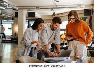 Multiracial young colleagues discussing project while working in office indoors - Powered by Shutterstock