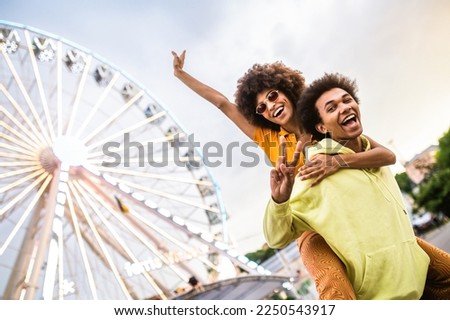 Multiracial young couple of lovers dating at theferry wheel in the amusement park - People having fun outdoors in the city- Friendship, releationship and lifestyle concepts