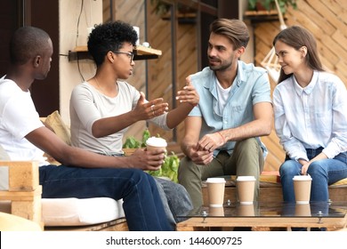 Multiracial Young Couples Sit In Coffeeshop Drinking Coffee Talking Sharing Ideas Relaxing Together, Multiethnic Millennial Friends Have Fun Enjoying Time In Café Chatting And Communicating