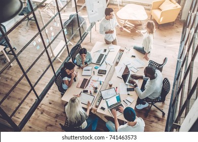 Multiracial young creative people in modern office. Group of young business people are working together with laptop, tablet, smart phone, notebook. Successful hipster team in coworking. Freelancers