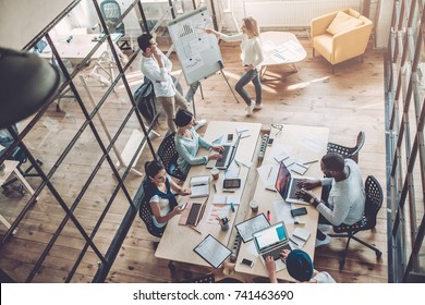 Multiracial Young Creative People In Modern Office. Group Of Young Business People Are Working Together With Laptop, Tablet, Smart Phone, Notebook. Successful Hipster Team In Coworking. Freelancers