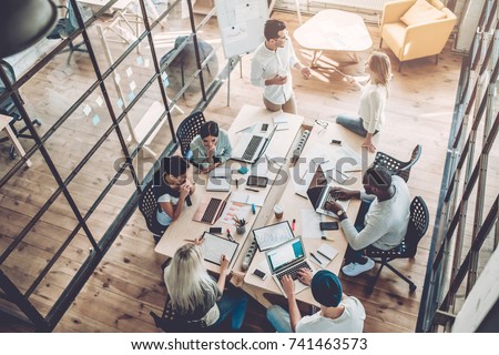 Multiracial young creative people in modern office. Group of young business people are working together with laptop, tablet, smart phone, notebook. Successful hipster team in coworking. Freelancers