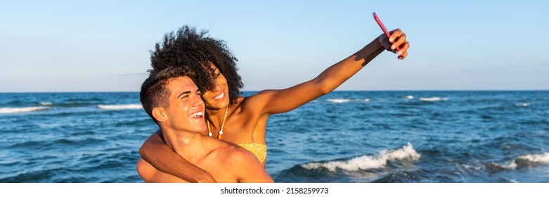 Multiracial young loving couple taking a selfie together on smartphone on beach – positive fun self portrait travelling multiethnic couple in love – happy travelling couple making a selfie - horizonta - Powered by Shutterstock