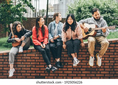 Multiracial young people playing guitar and singing on street. - Powered by Shutterstock