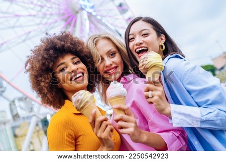 Multiracial young people together meeting at amusement park and eating ice creams - Group of friends having fun outdoors - Friendship and lifestyle concepts