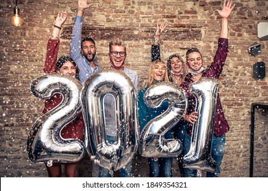 Multiracial young smiling friends are celebrating new year's eve party in house  in covid-19 time - Group of young people holding balloons looking at camera and smile all together throwing confetti - Powered by Shutterstock