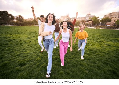 Multiracial youth excited group having fun and running around green meadow. Outdoor recreational activities with friends and fun on sunny day in city park. Healthy and positive relationships. - Powered by Shutterstock