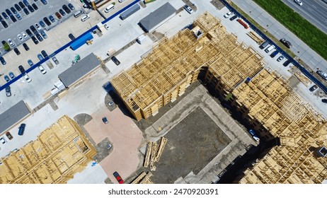 Multistory apartment complex under construction with timber wood frame, elevator vertical shaft, large courtyard, slab foundation, heavy equipment machines, downtown Dallas, Texas, aerial view. USA