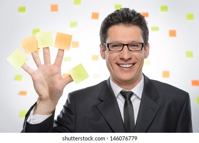 Multi-tasking businessman. Portrait of cheerful businessman showing his hand with sticky notes on each finger