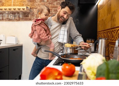 Multitasking father babysitting, cooking breakfast and talking on smart phone at home. - Powered by Shutterstock