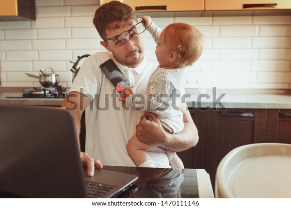 Multitasking Father Working From Home On Laptop\
With Baby daughter