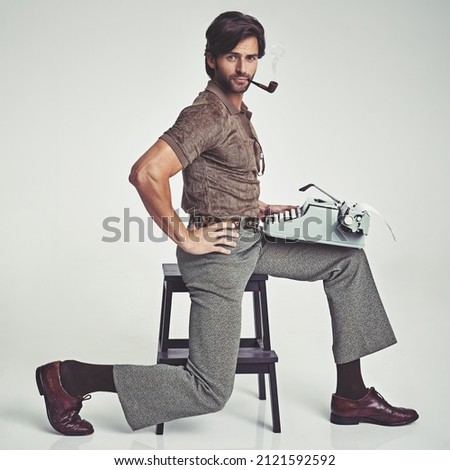 Multi-tasking to the max. Studio shot of a 70's style businessman sitting on a stool using a typewriter.