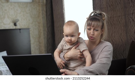 Multitasking Mom Holding Baby Working From Home Using Computer. Kid Plays With His Mother Working Remotely At Laptop In Room. Happy Family At Home Mommy Baby. Family Teamwork. Beloved Little Son