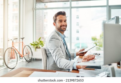 Multitasking My Way To Success. Portrait Of A Handsome Young Businessman Working On A Laptop And Digital Tablet In An Office.