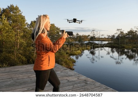 Multitasking videographer at work: a woman simultaneously shoots with a camera and operates a drone, creating content from different angles in nature.