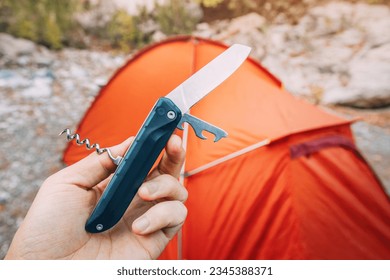 multitool foldable knife against camping tent background during hike