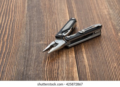 Multitool on wooden surface. Improved construction tools. Everyday instruments and tools. Progress. Construction and Repair.