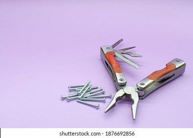 multitool turned into pliers, knife, screwdriver on violet background, screws. repairing. fix. High quality photo copy space. place for your text
