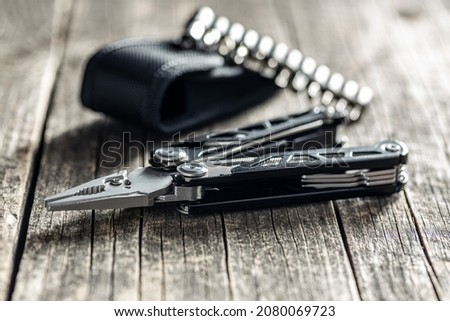 Multi-tools pliers with other tools and knife. Multifunction pliers on wooden table.