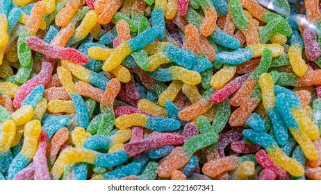 A Multitude Of Colorful Food Sour Worms As Bombons Lying Next To Each Other. Texture Of A Candy Or Sweets Covered With Sugar.