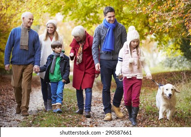 Multl Generation Family Walking Along Autumn Path With Dog