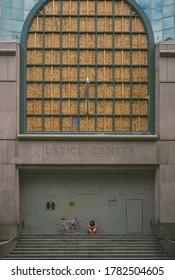 Multnomah County Justice Center Portland, Oregon - July 23rd, 2020: 
A Man Sits Peacefully In All Pink, While In Front Of The Barricaded Justice Center. 