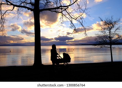 Mum with the buggy silhouette in front of the lake sunrise of lake Geneva in Switzerland - Powered by Shutterstock