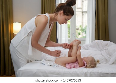 Mum Changing A Baby's Diaper On The Bed In The Bedroom