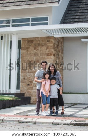 mum and dad with their child smiling to camera infront of the house
